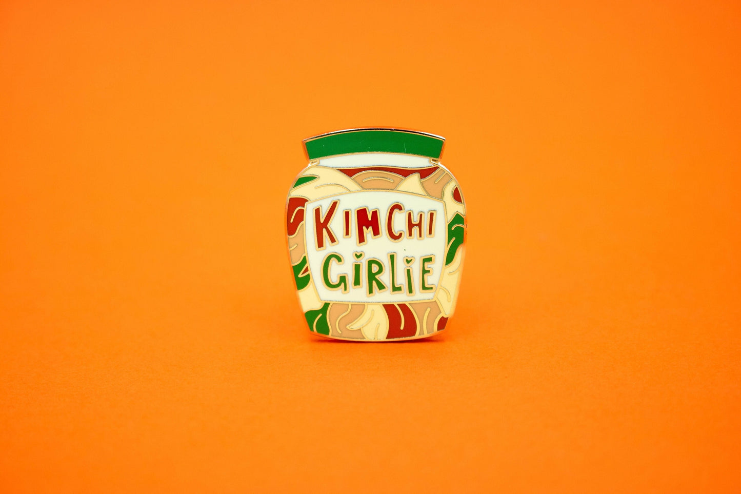 enamel pin in the shape of a jar of kimchi with the words 'kimchi girlie'
