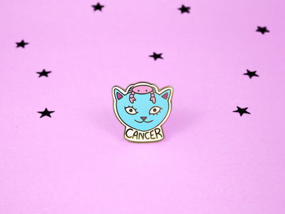 Cancer cat enamel pin in pink colour with a crab on its head and cancer constellation speckled across its face.