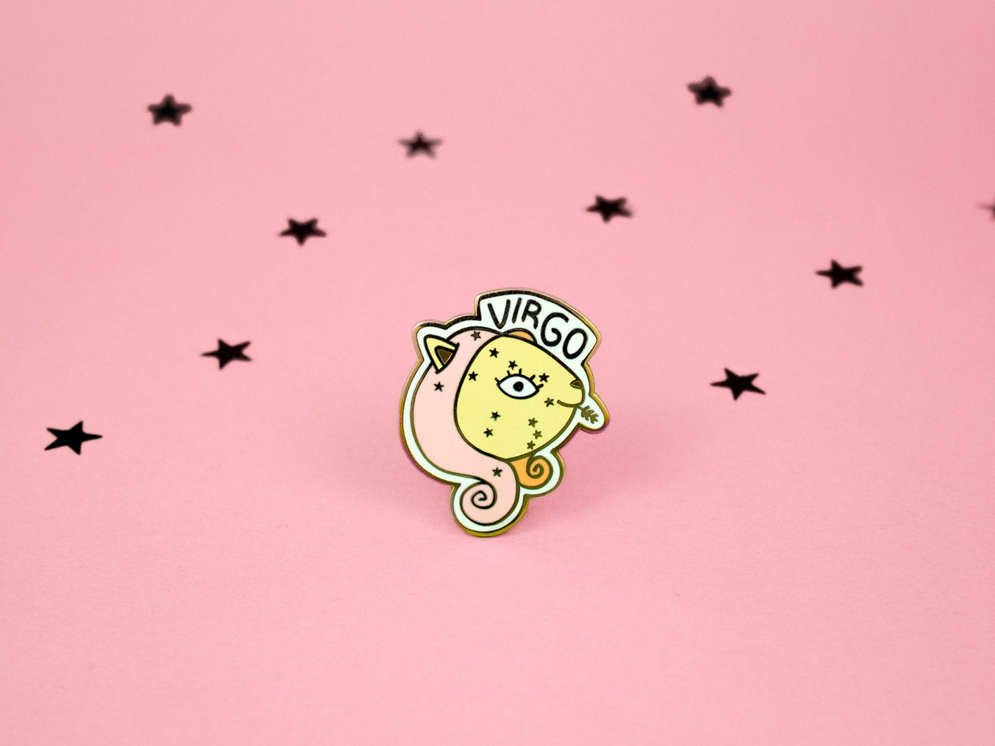 enamel pin of virgo cat in pink yellow and orange colours with a wheat stalk in it&#39;s mouth and the virgo constellation on its face and the word virgo above