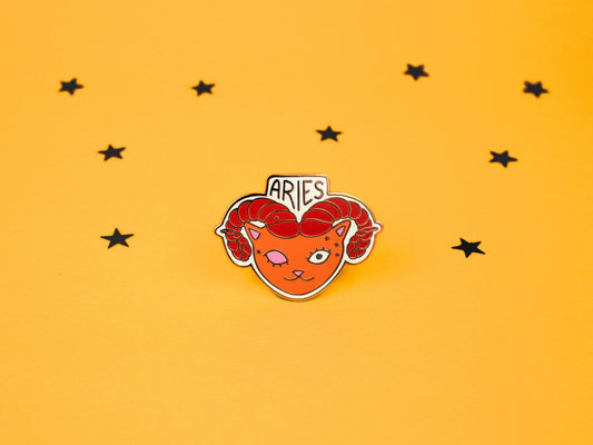 aries the ram cat enamel pin in orange and red colour with rams horns and aries constellation speckled across its face