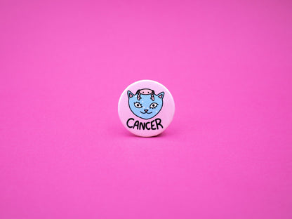 Pink button badge featuring a blue cat with small pink crab on its head to represent cancer zodiac and the word &#39;CANCER&#39; below