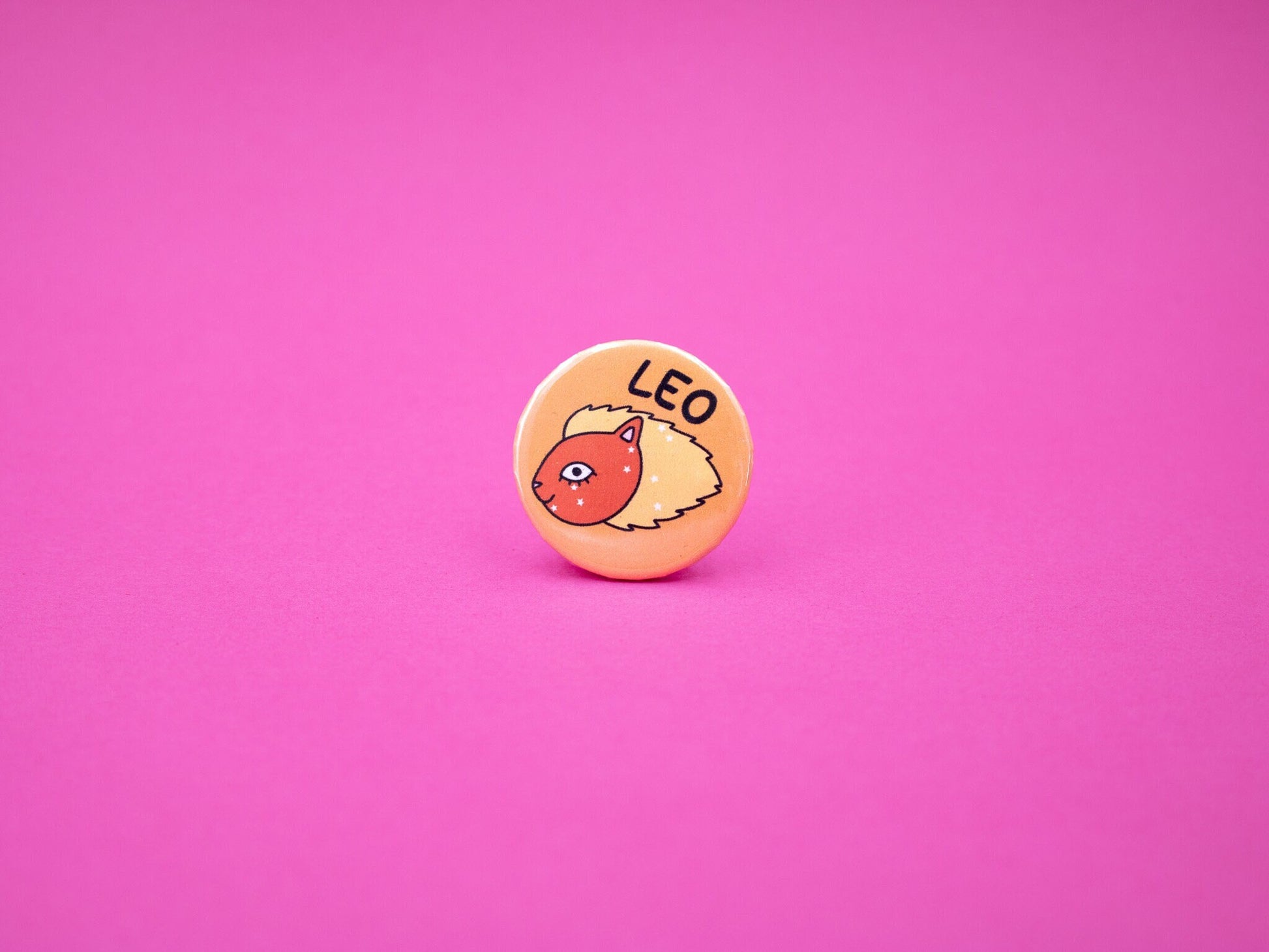 orange and red button badge featuring leo the lion as a cat with leo constellation across its face in stars