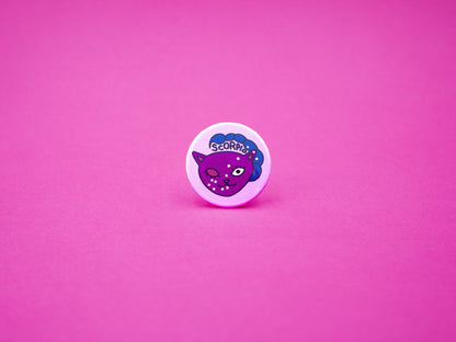 purple badge featuring a winking cat with a scorpion tail and the word scorpio