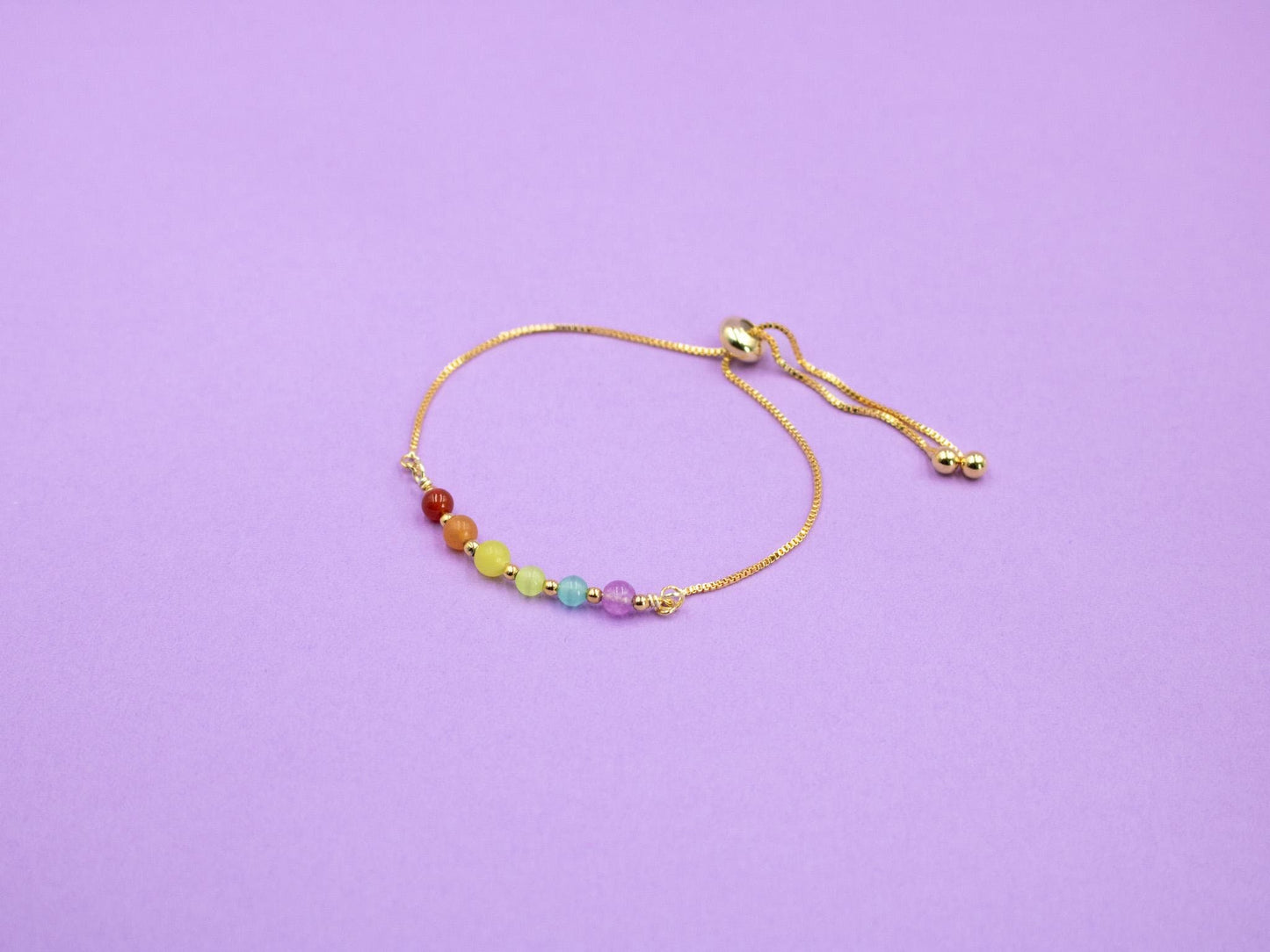 gold adjustable bracelet with gemstone beads in the colours of the LGBTQIA flag