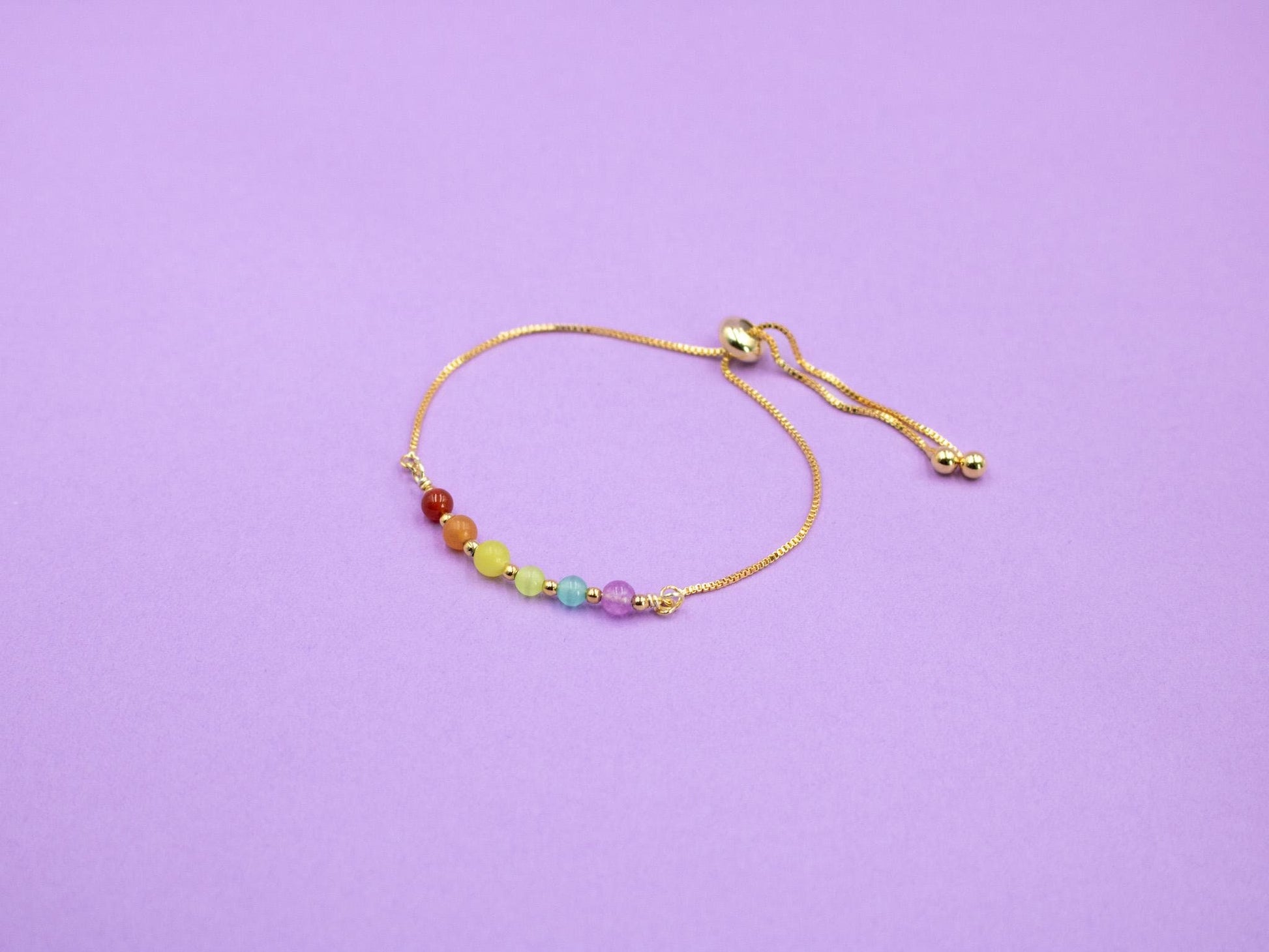 gold adjustable bracelet with gemstone beads in the colours of the LGBTQIA flag
