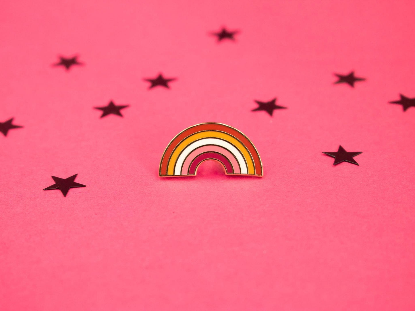 hard enamel pin in the shape of the rainbow with the colours of the lesbian flag making up the stripes