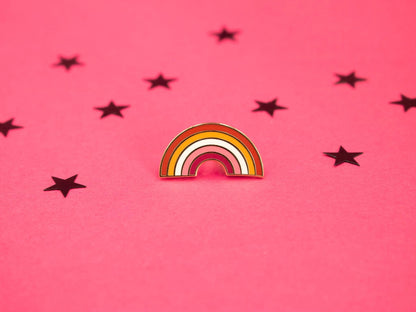 hard enamel pin in the shape of the rainbow with the colours of the lesbian flag making up the stripes